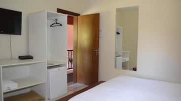 A hotel room with a bed, a wardrobe, a small desk with a computer, a TV mounted on the wall, and a door leading to a balcony.