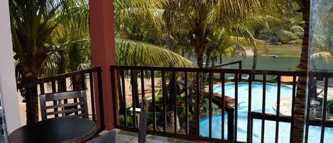 Un balcón con vista a una piscina y palmeras.