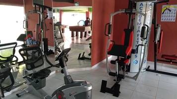 A gym with cardio equipment, weight machines, and a mirrored wall.