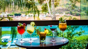 Una mesa con cuatro bebidas y vistas a un lago y árboles.