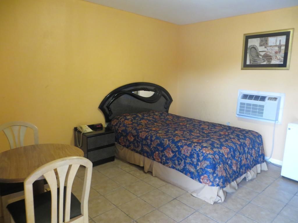 Una habitación de hotel pequeña y sencilla, con cama, escritorio y silla.
