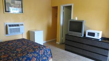 A hotel room with a bed, a television, a microwave, and a dresser.