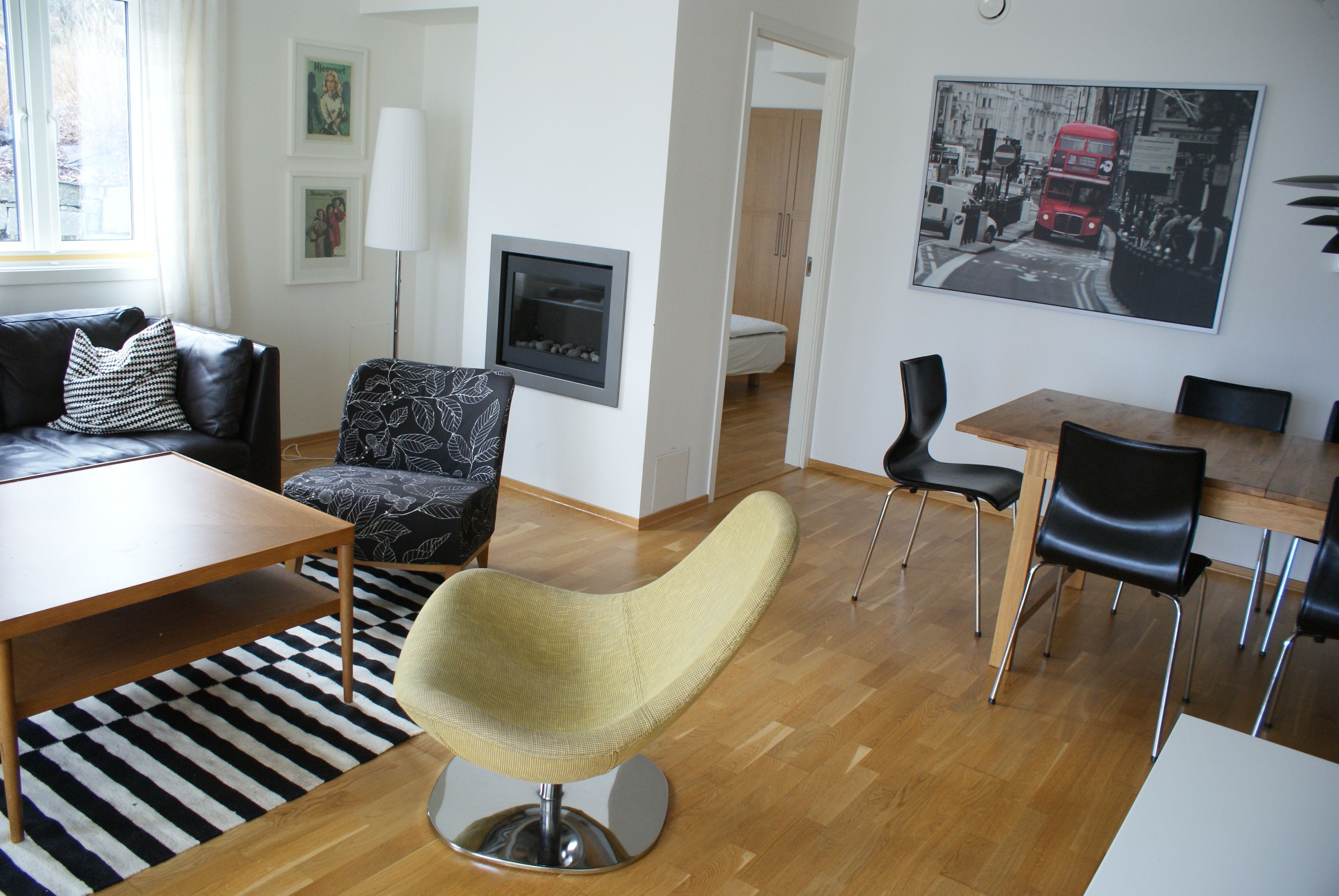 A modern living room with a sofa, a yellow armchair, a dining table, and a black and white patterned rug.