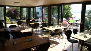 An indoor dining area with large windows, wooden tables, and chairs. - Fjordbris Hotell (Stavanger)