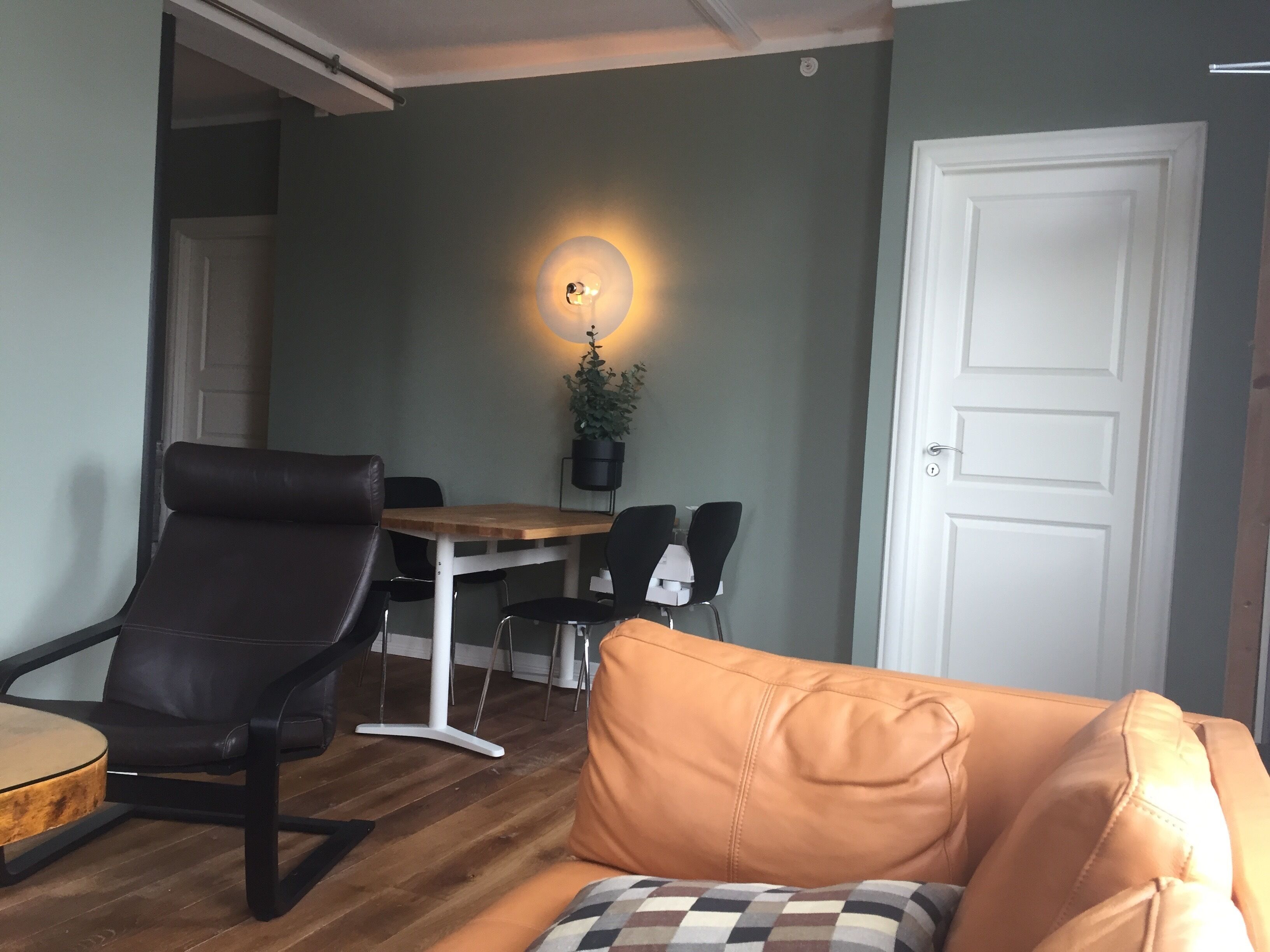 A living room with a brown leather sofa, a wooden coffee table, and a dining area with a wooden table and chairs.