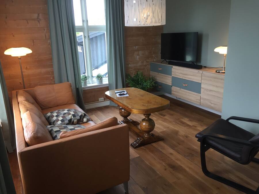 A modern living room with a sofa, a wooden coffee table, a TV, and a desk with drawers.