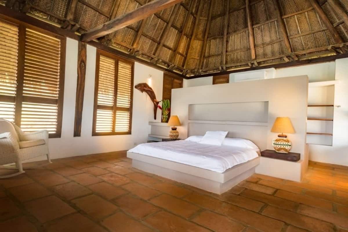 Un dormitorio con una cama grande, cabecera de madera y dos mesitas de noche con lámparas.