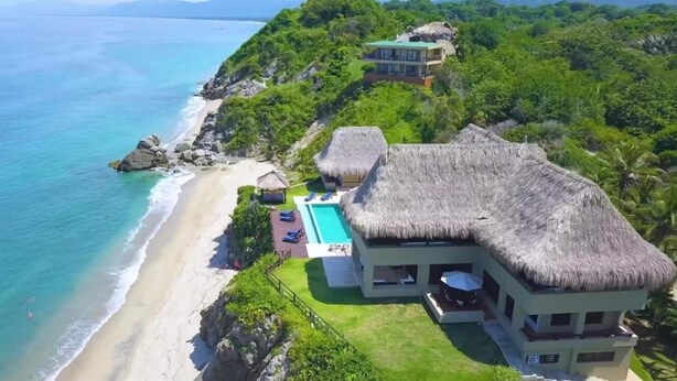 A beachfront property with a pool, thatched-roof structures, and lush greenery. - Casa Tayrona los Naranjos (Santa Marta)