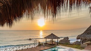 A pool area with lounge chairs and umbrellas, overlooking the ocean at sunset. - Casa Tayrona los Naranjos (Santa Marta)