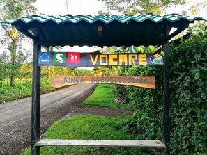 A wooden sign with "VODCARE" and "FINCA AGRICOLOGICA" written on it, mounted on a metal structure with a corrugated roof.