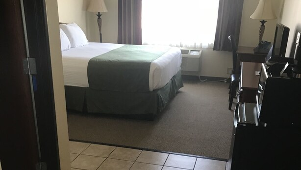 A hotel room with a bed, two bedside tables, a desk, and a chair. - Edgewood Hotel & Suites (Fairbury)