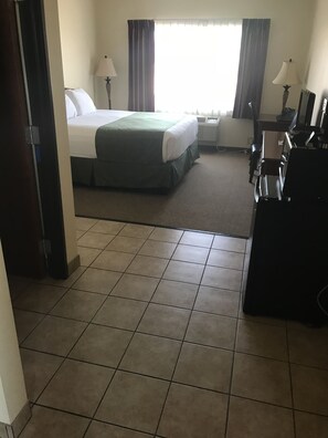 A hotel room with a bed, two bedside tables, a desk, and a chair. - Edgewood Hotel & Suites (Fairbury)