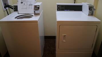 A laundry area with two washing machines and a dryer.