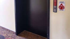 An elevator with emergency instructions on the wall, including a sign advising to use stairs in case of fire and to use the exit if elevators are out of service. - Edgewood Hotel & Suites (Fairbury)