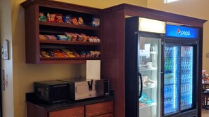 A kitchenette with a microwave, a coffee maker, and a refrigerator stocked with beverages. - Edgewood Hotel & Suites (Fairbury)