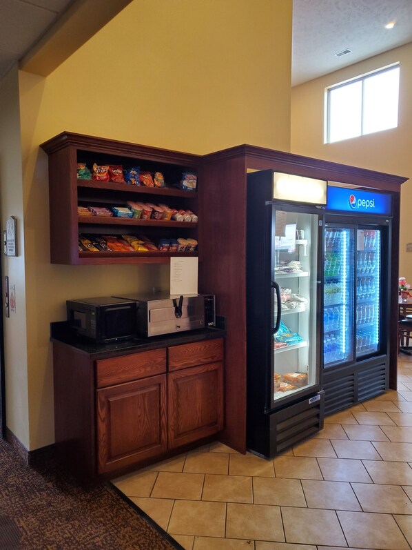 A kitchenette with a microwave, a coffee maker, and a refrigerator stocked with beverages. - Edgewood Hotel & Suites (Fairbury)