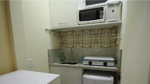 A compact kitchen with a microwave, a small refrigerator, and a sink. - Copacabana 1007 (Rio de Janeiro)