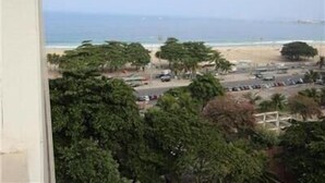 A beach view with palm trees and a parking lot. - Copacabana 1007 (Rio de Janeiro)