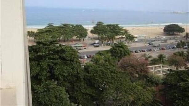 A beach view with palm trees and a parking lot. - Copacabana 1007 (Rio de Janeiro)