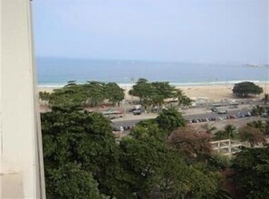 Vista da praia com palmeiras e um estacionamento.