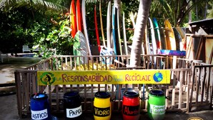 Een inzamelpunt met daarop labels voor verschillende materialen en een bord dat ecologisch bewustzijn stimuleert.