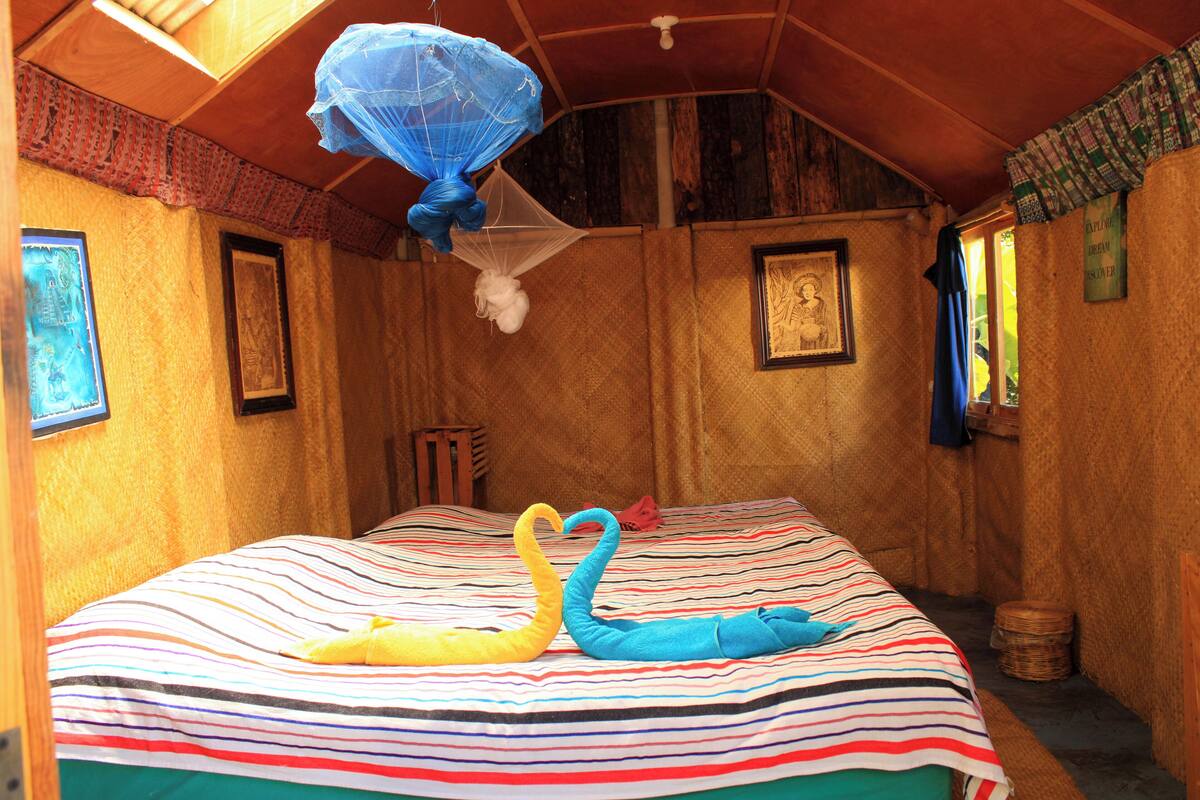 Een kamer met een bed, een klamboe en een lijst met een afbeelding aan de muur.