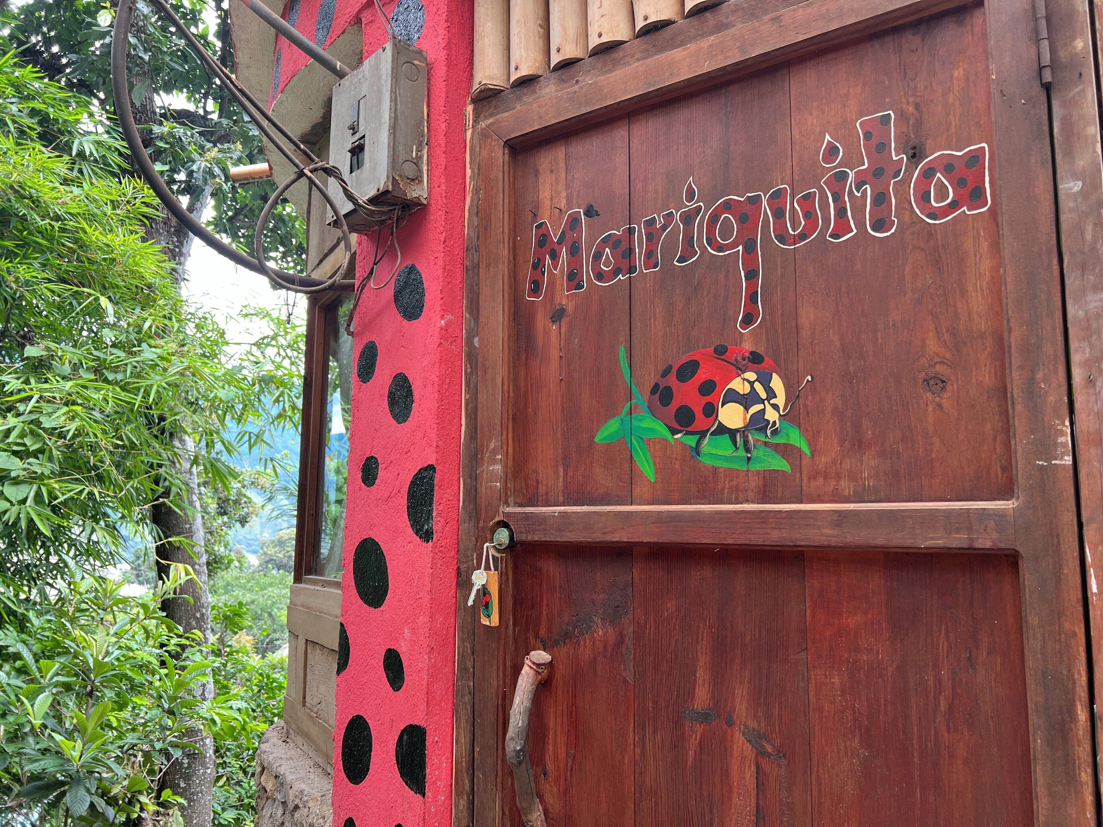 A wooden door with a ladybug design and the name 'Mariquita' painted on it.