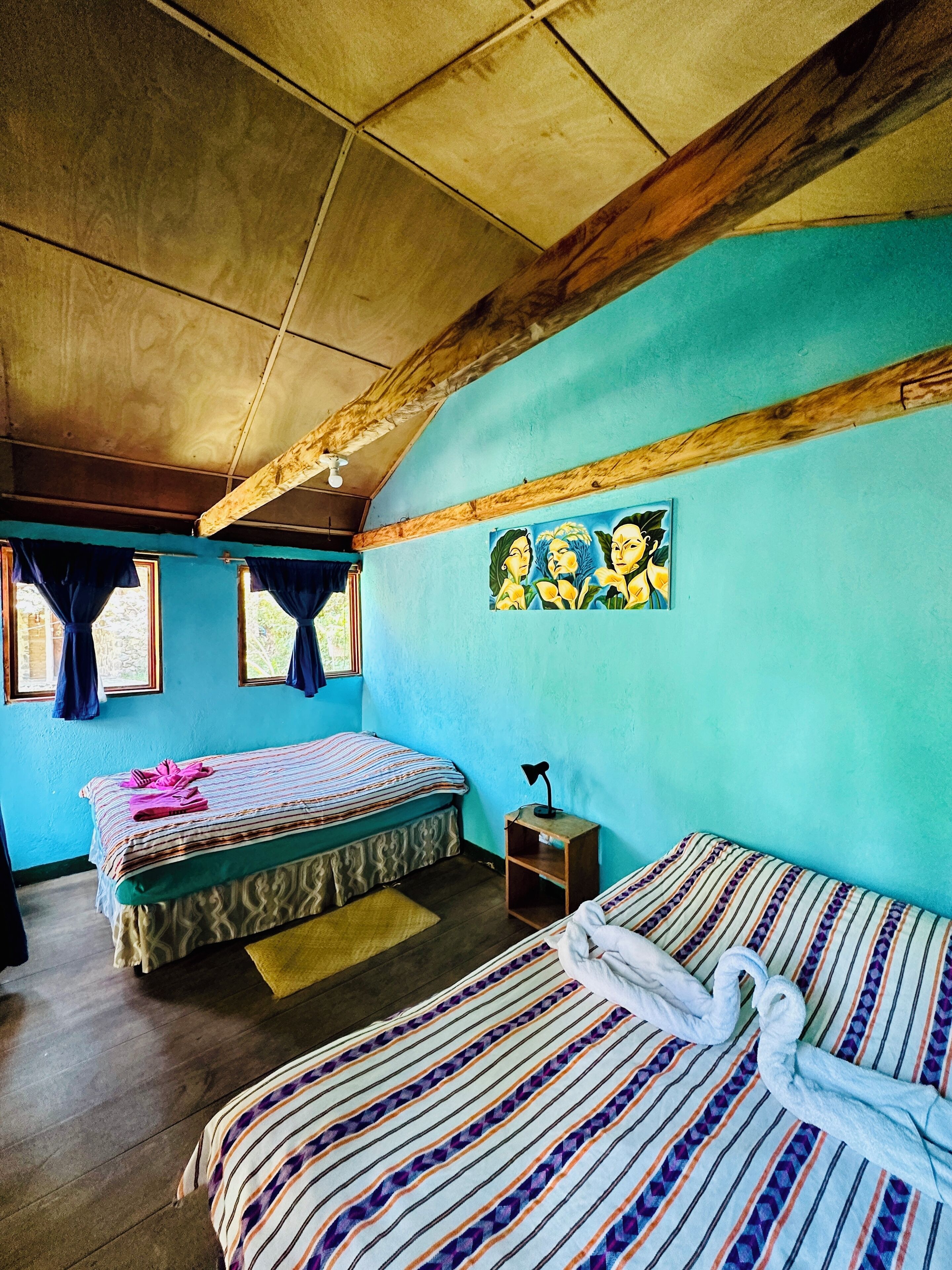 Een kamer met twee bedden, een klein tafeltje en een schilderij aan de muur.