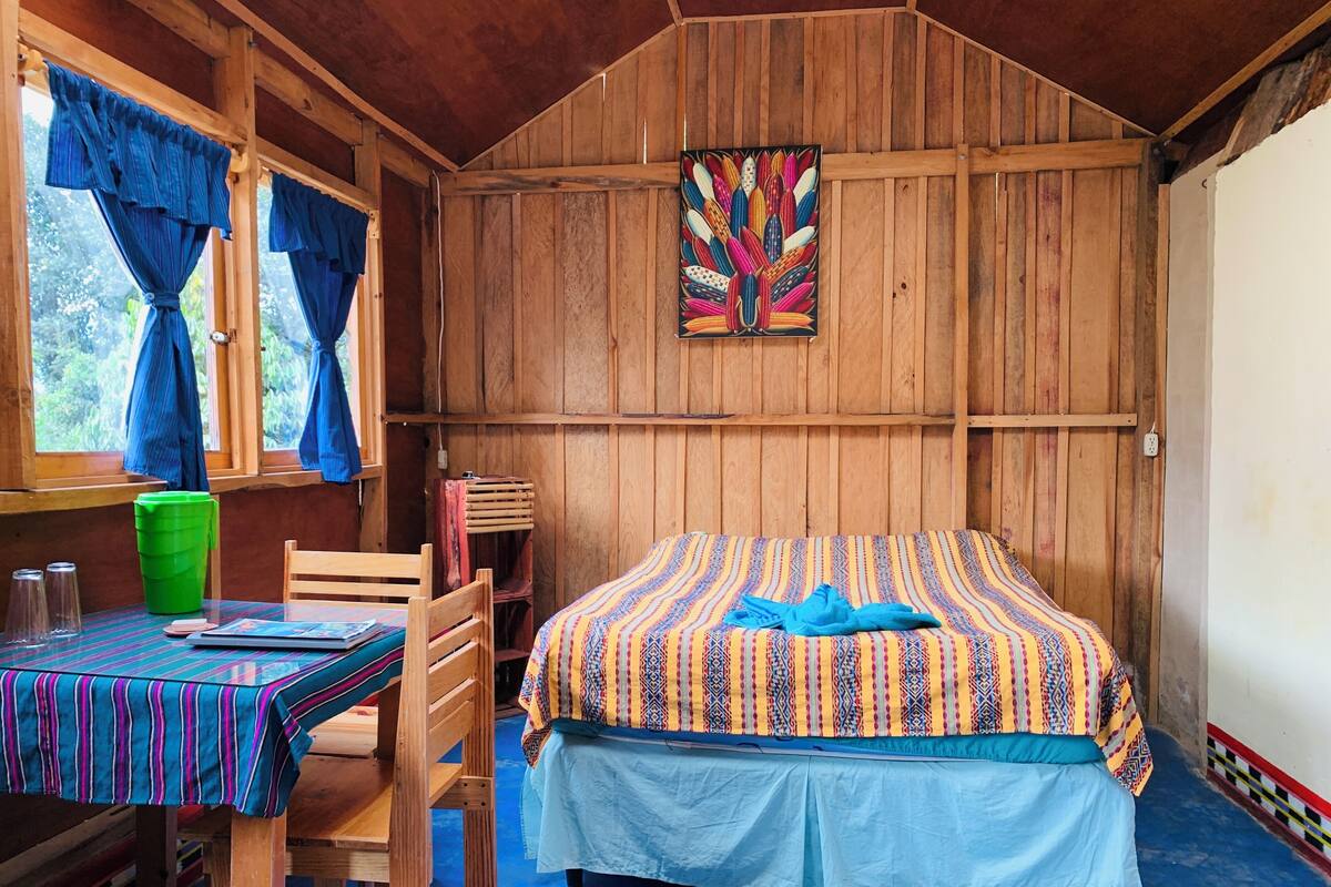 Een houten kamer met een bed, een tafel en een stoel.