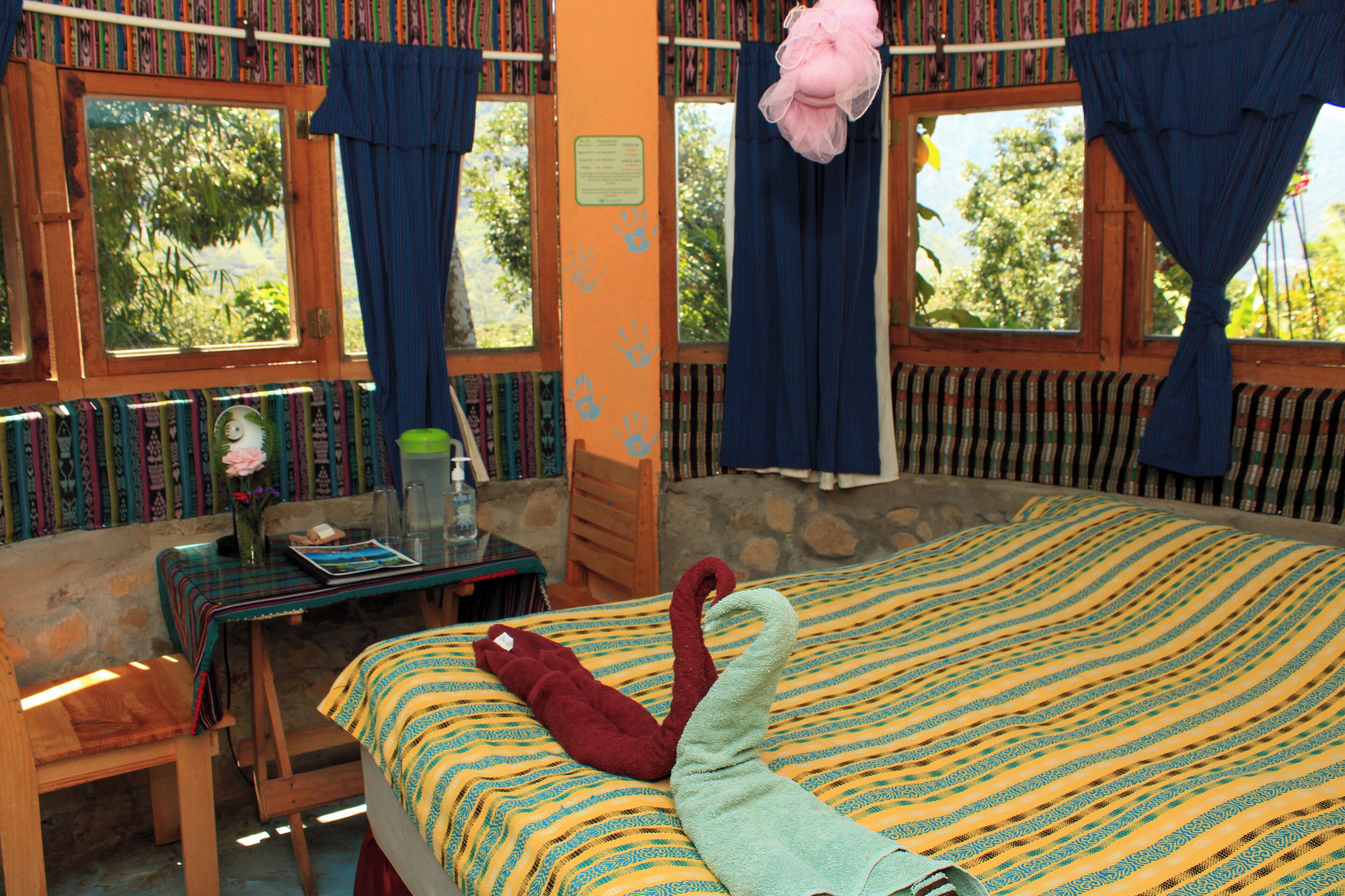 A room with a bed, a table, and a window with curtains.