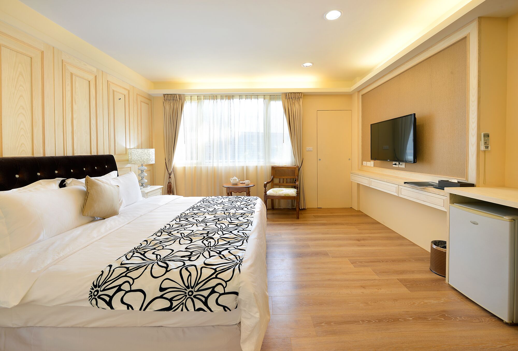 A hotel room with a bed, a TV, a desk, and a chair.