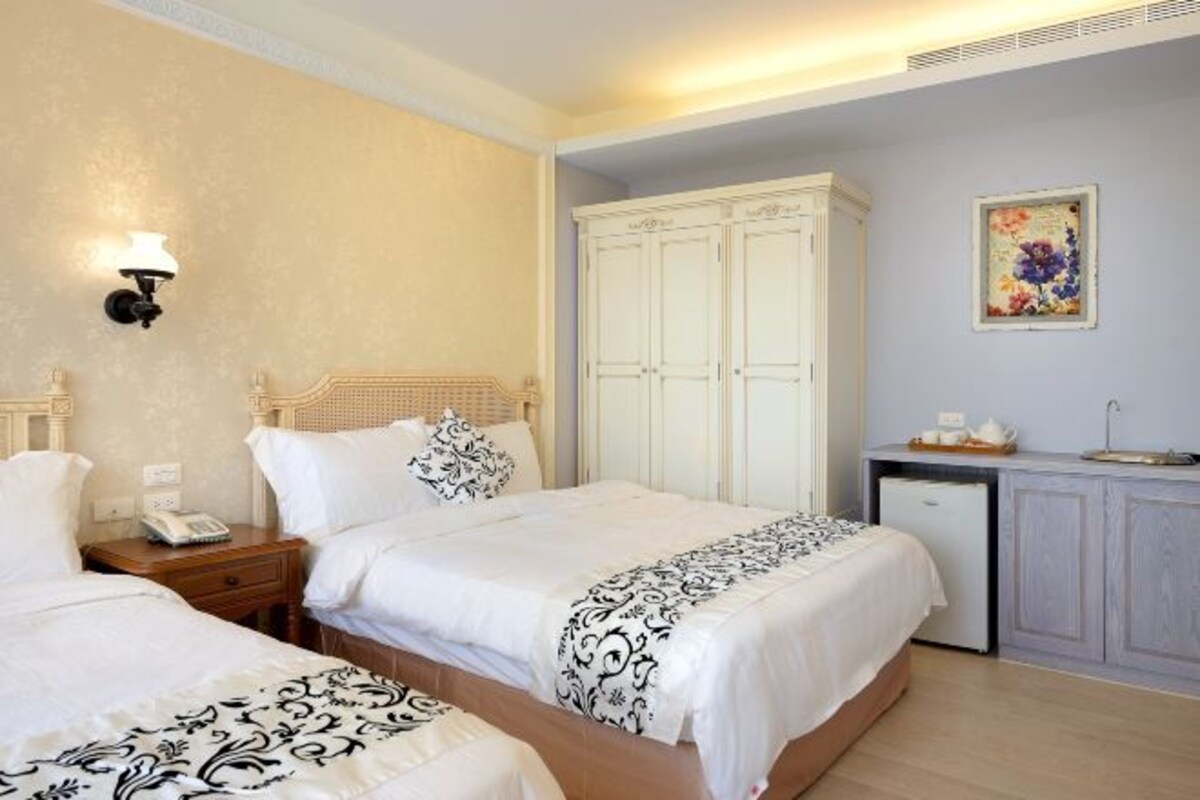Ein Hotelzimmer mit zwei Betten, einer kleinen Küchenzeile und einem Kleiderschrank.
