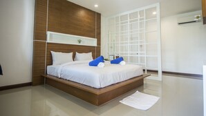 A modern bedroom with a wooden headboard, a large bed, and a white bedside table. - Phuphayot Resort (Huai Yot)