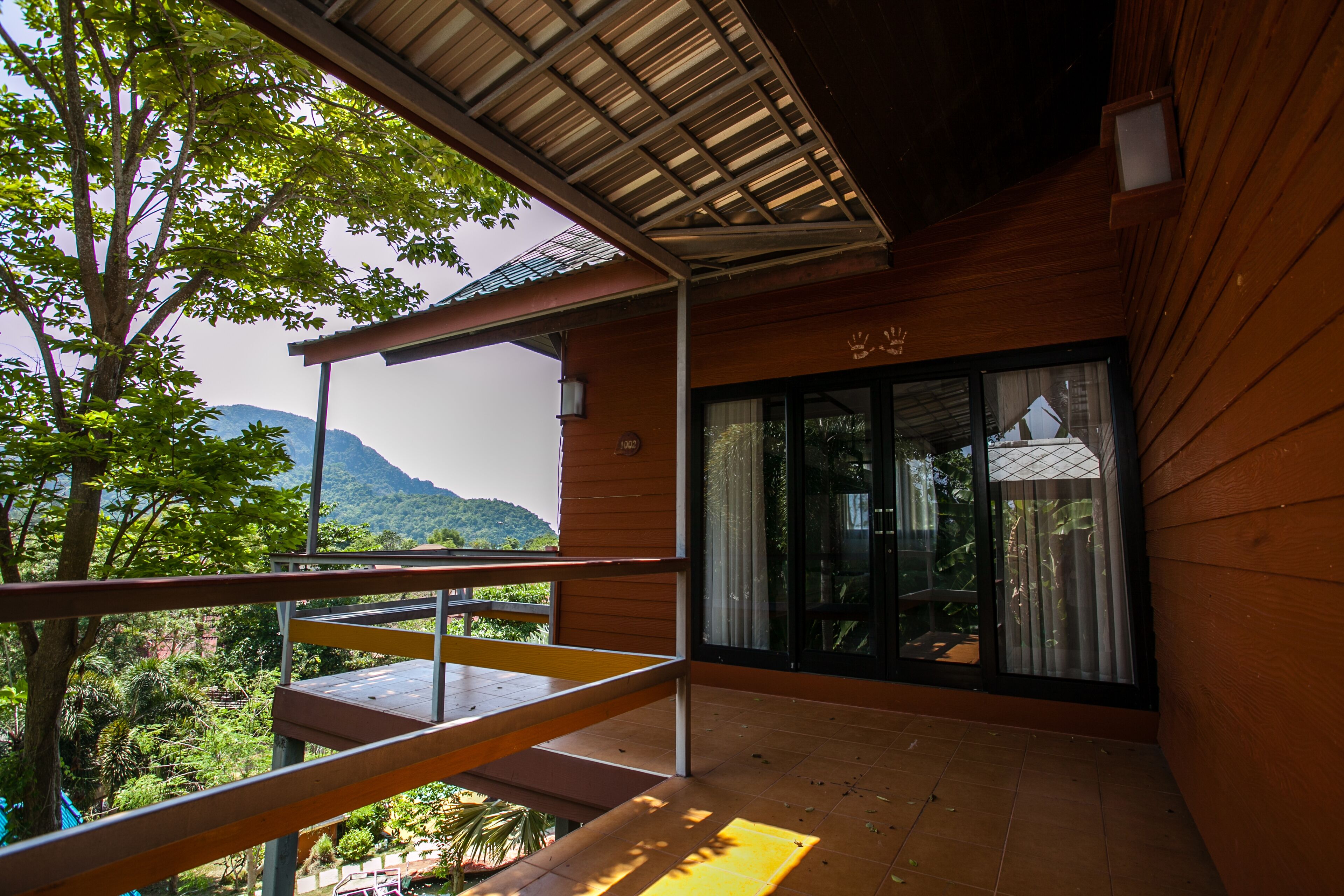 A wooden balcony with a view of lush greenery and mountains.