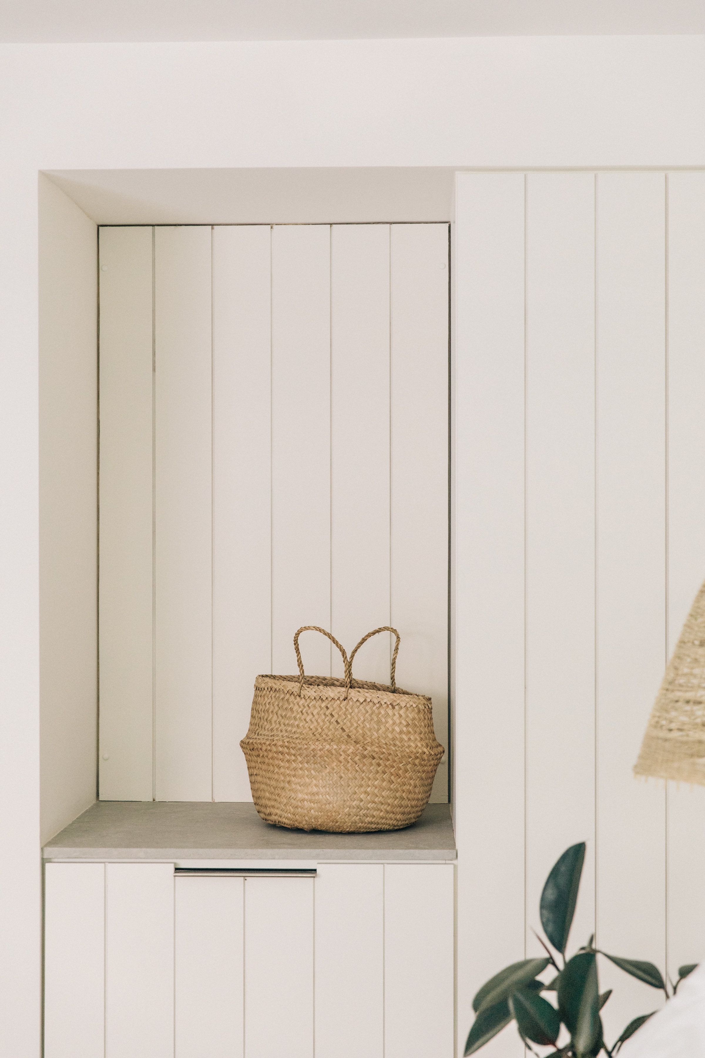 A white cabinet with a woven basket on top.