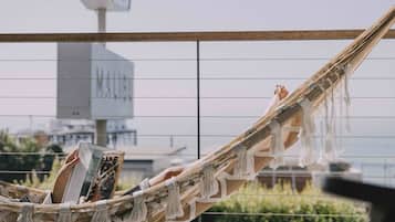 A hammock with a person reading a book, a bottle of water, and a view of a building with a sign.