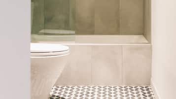 Un baño moderno con ducha, inodoro y baldosas de suelo estampadas.