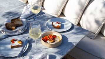 Una mesa servida con platos de comida, una copa de vino blanco y cubiertos.