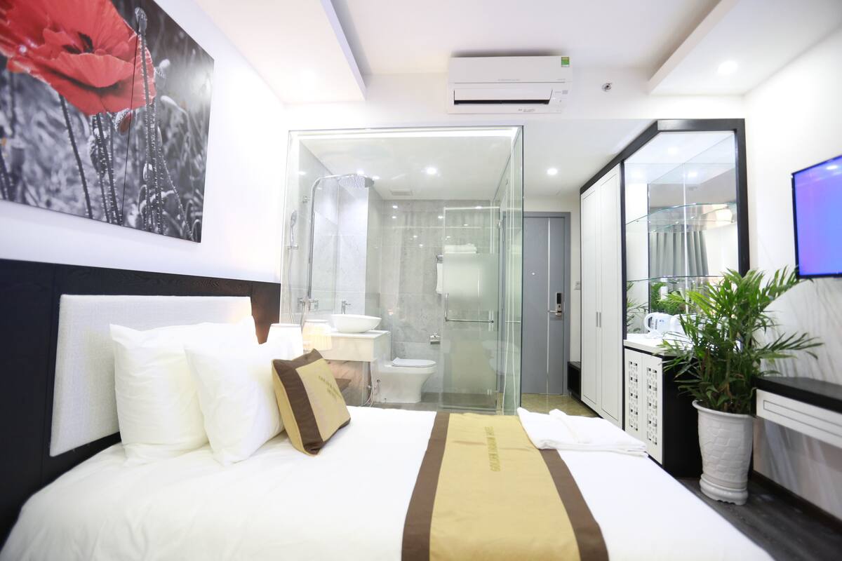 Une chambre d’hôtel moderne équipée d’un lit, d’une douche en verre, d’un lavabo et d’une plante en pot.