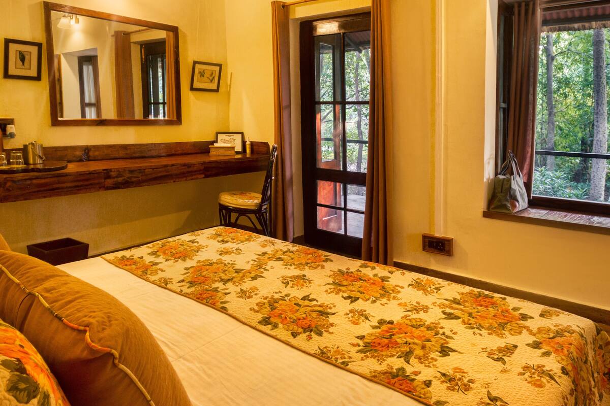 A bedroom with a bed, a chair, a window, and a door leading outside.
