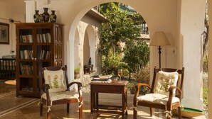 A cozy reading nook with a wooden chair, a small table, and a bookshelf filled with books. - Jim's Jungle Retreat (Ramnagar)