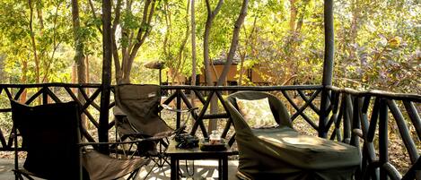 An outdoor seating area with a table and chairs, surrounded by a wooden fence and trees.