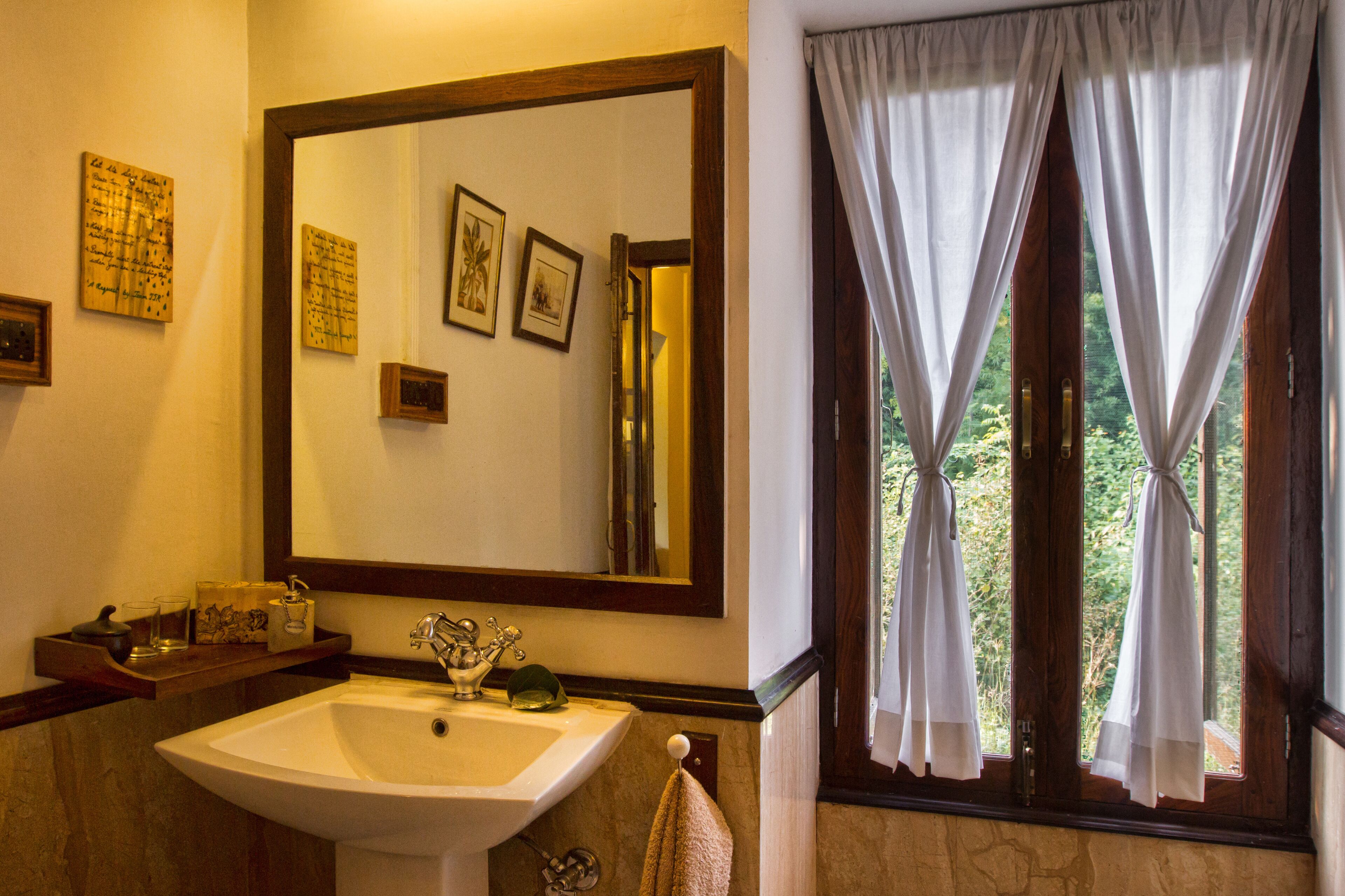 Un baño con un espejo grande, un lavamanos y una ventana con cortinas.