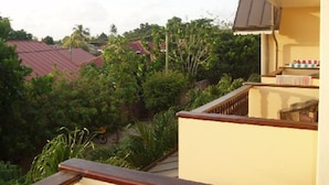 A balcony with a view of neighboring houses and greenery. - Gregoire's Apartments (La Digue)