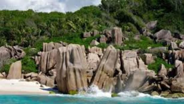 A coastal landscape with rocky formations and a beach. - Gregoire's Apartments (La Digue)