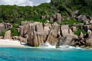 A coastal landscape with rocky formations and a beach. - Gregoire's Apartments (La Digue)