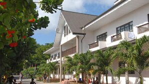 A building with a white facade, multiple windows, and a balcony. - Gregoire's Apartments (La Digue)