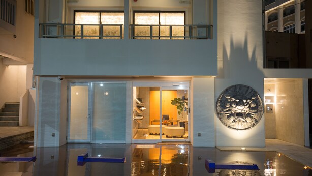 A modern hotel with a glass entrance, a reception area, and a decorative wall sculpture. - Condominio Makishi Annesso (Naha)