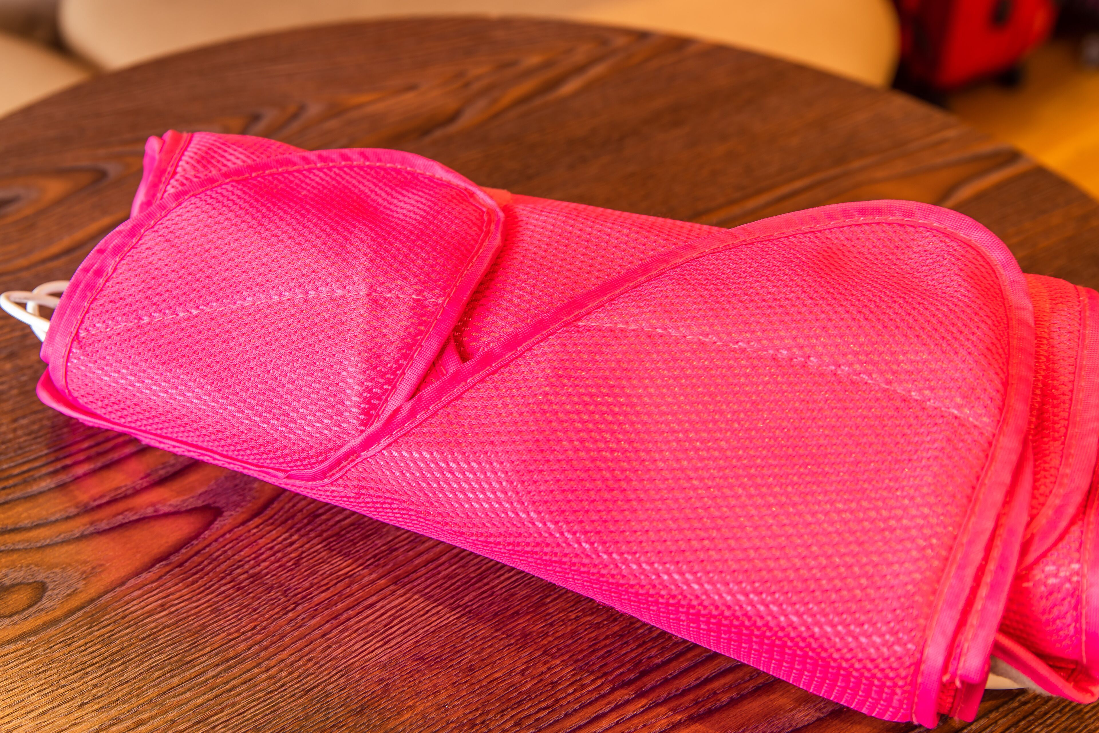 A pink mesh bag on a wooden table.