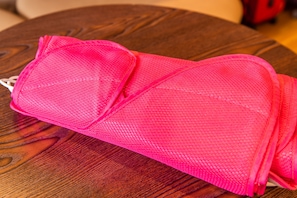 A pink mesh bag on a wooden table.